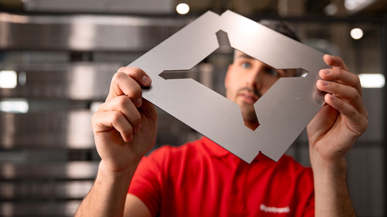 Bystronic employee inspecting a precision-cut sheet metal component
